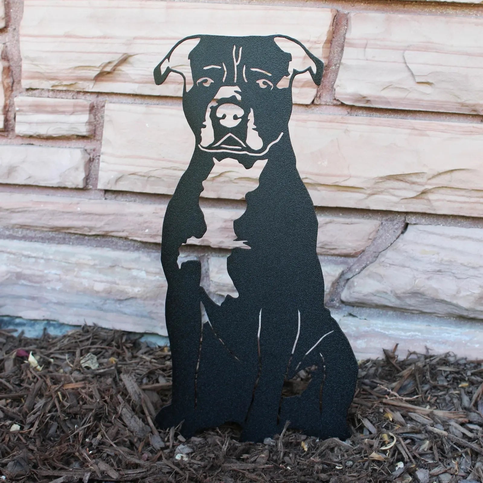 Black metal silhouette of a Staffordshire Bull Terrier sits against a textured stone background, perfect for outdoor decor.