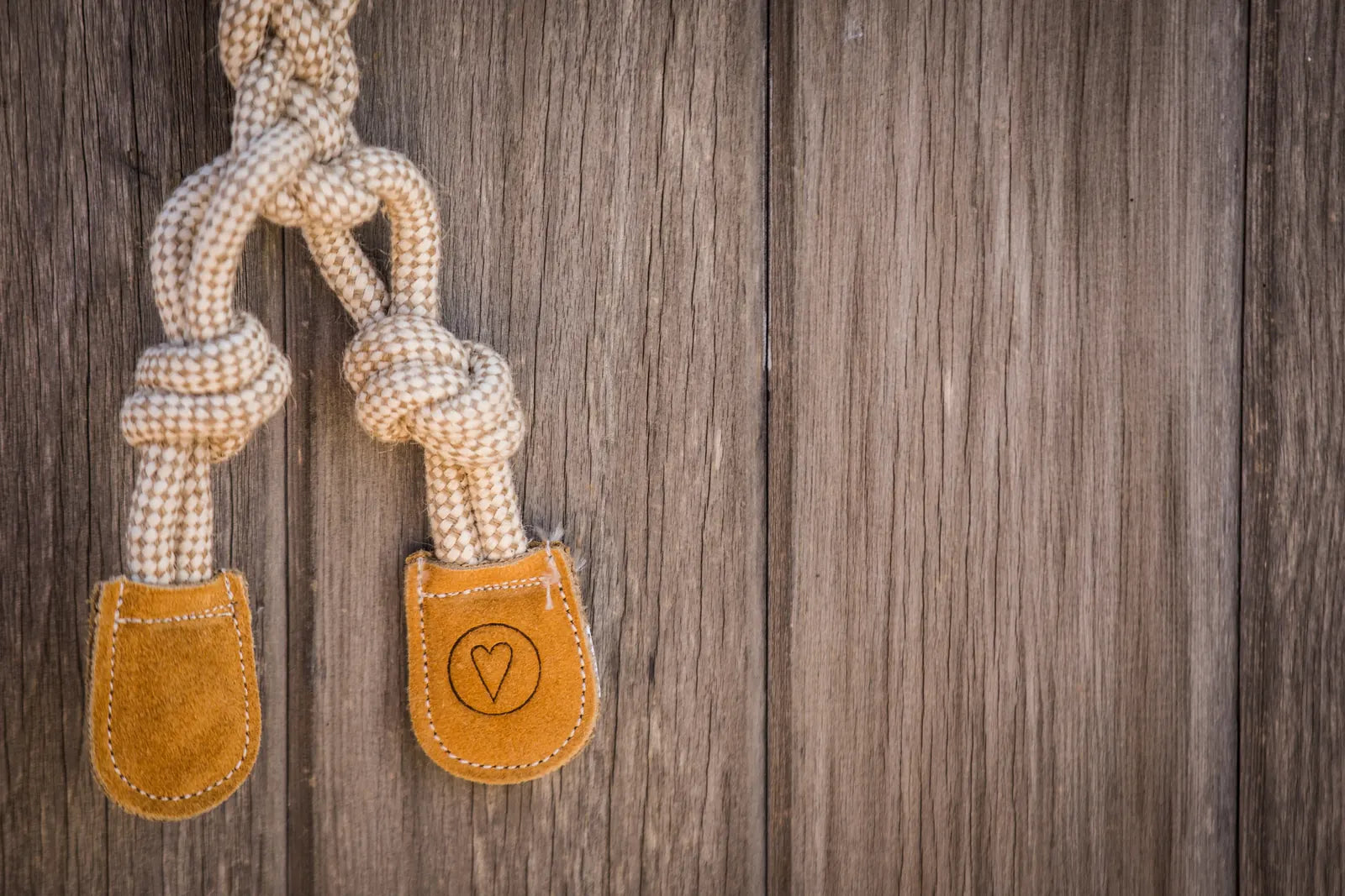 Natural rope dog toy with hand-knotted cotton, featuring suede leather accents in a heart shape on the ends.