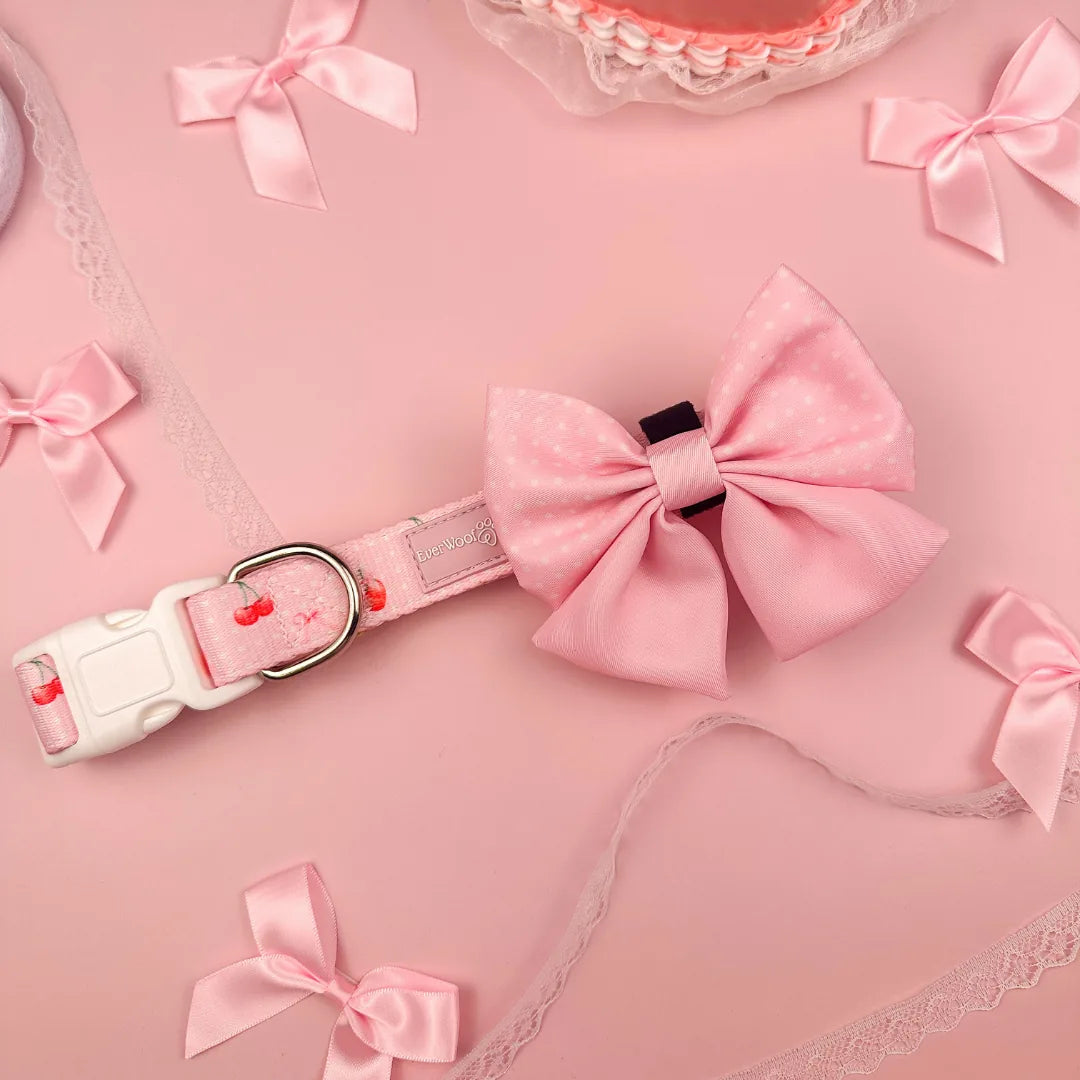 Adjustable pink collar with a large polka-dot bow and floral design on the strap, surrounded by matching decorative ribbons.