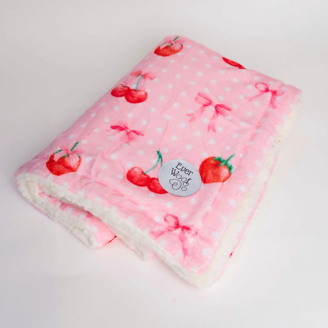 Pink dog blanket with cherry and bow patterns, featuring a soft micro-fiber side and cream sherpa lining.