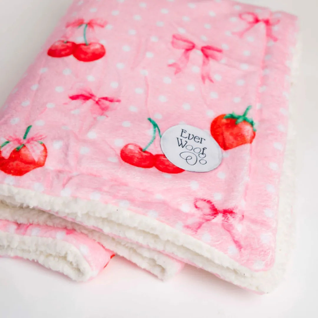 Soft pink dog blanket with cherry and polka dot pattern, featuring a cream sherpa side and EverWoof logo.