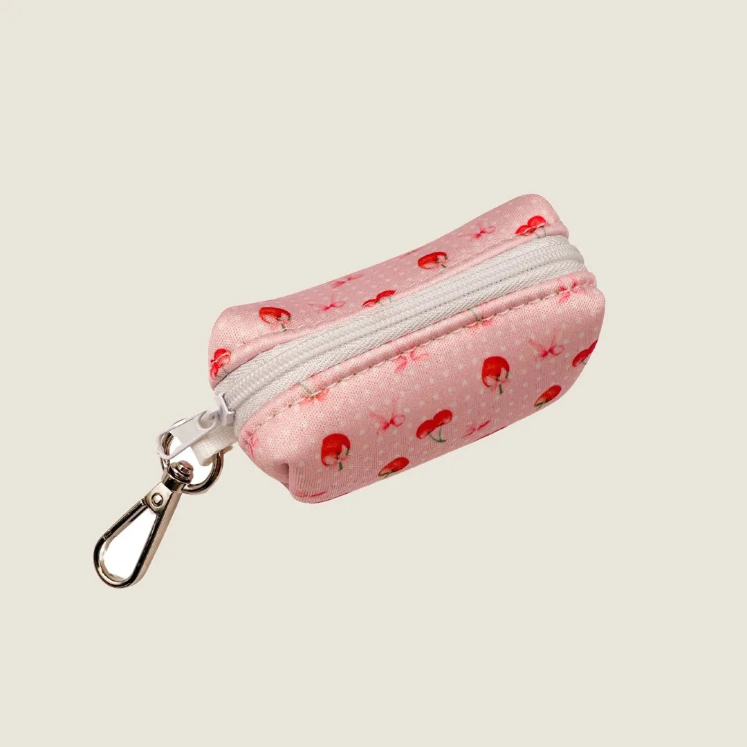 Light pink waste bag holder with red strawberries and white polka dots, featuring a zip closure and metal clip.
