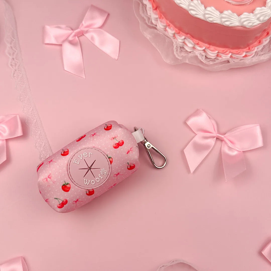Light pink waste bag holder with cherry pattern and zinc alloy hook, surrounded by pink bows on a pastel background.