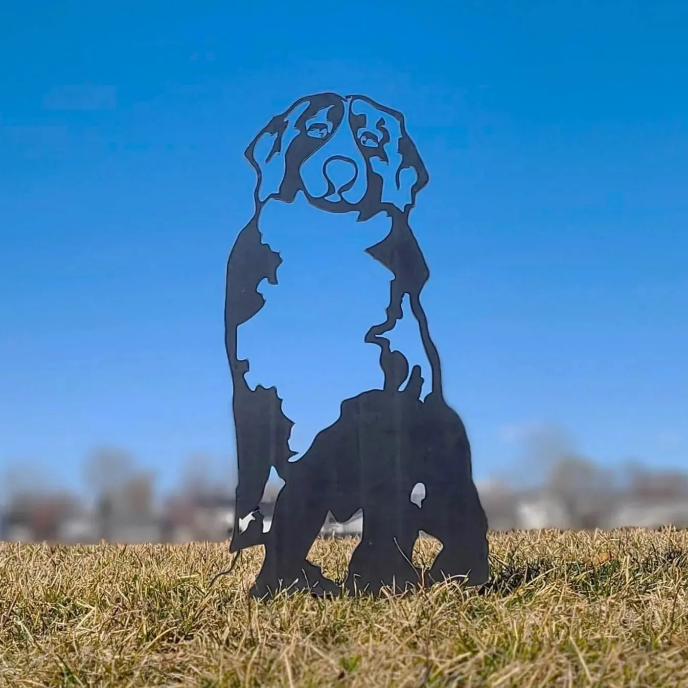 Swiss Mountain Dog silhouette in matte black metal stands tall in grass under a clear blue sky, perfect for outdoor decor.