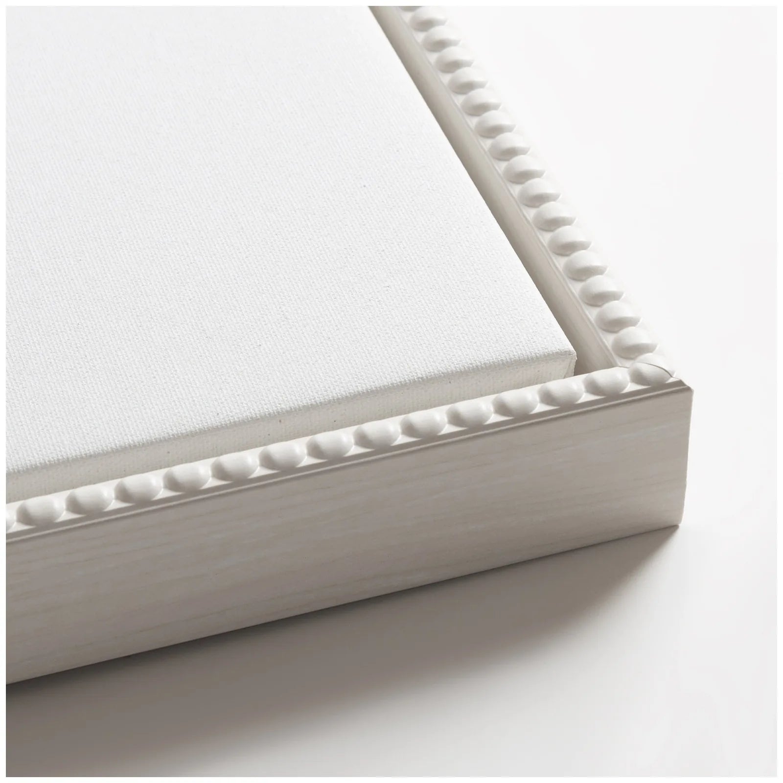 Close-up of a gallery-wrapped canvas with a textured white frame featuring a vintage beaded design.