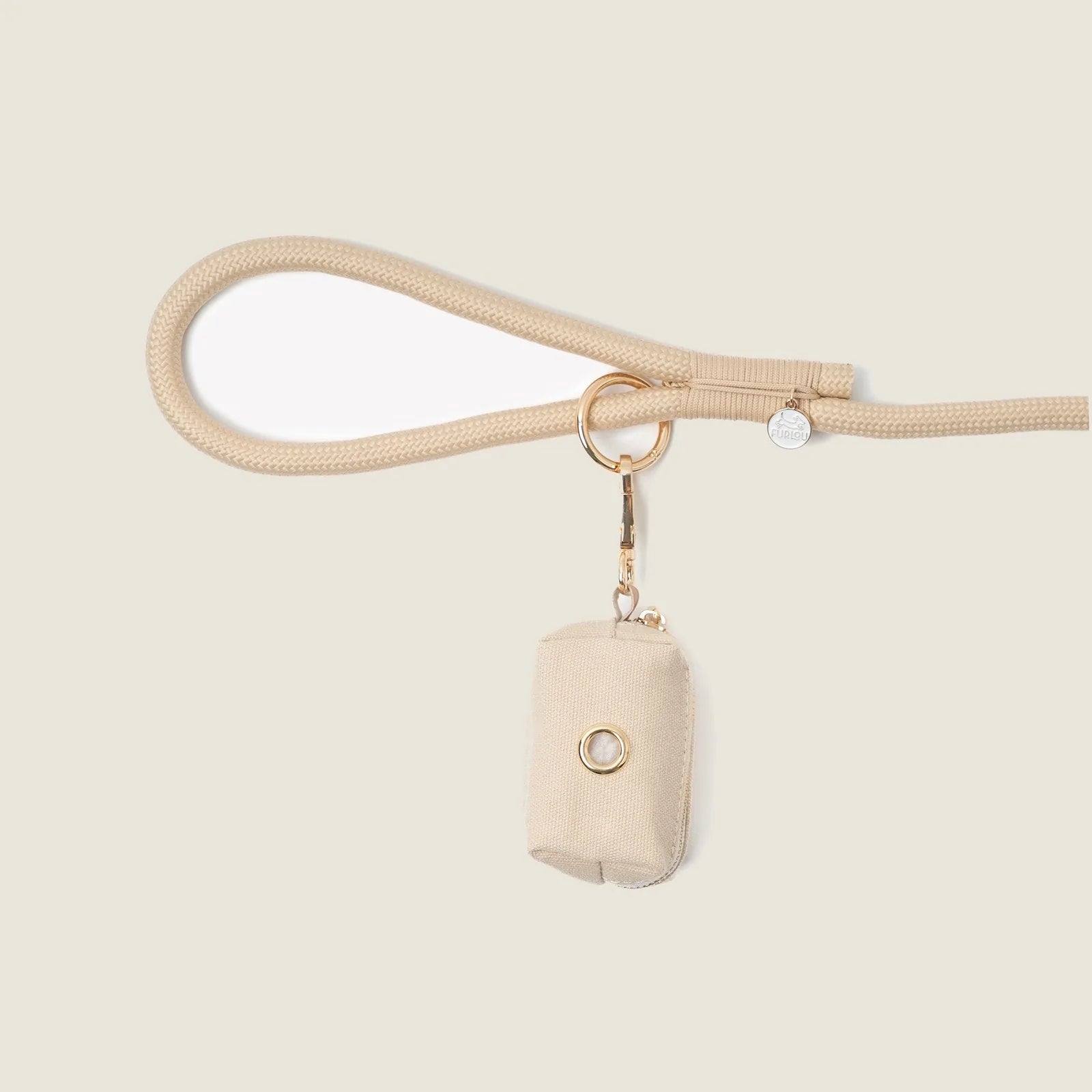Tan poop bag holder by FURLOU clipped to a beige leash, featuring a simple design and gold hardware.