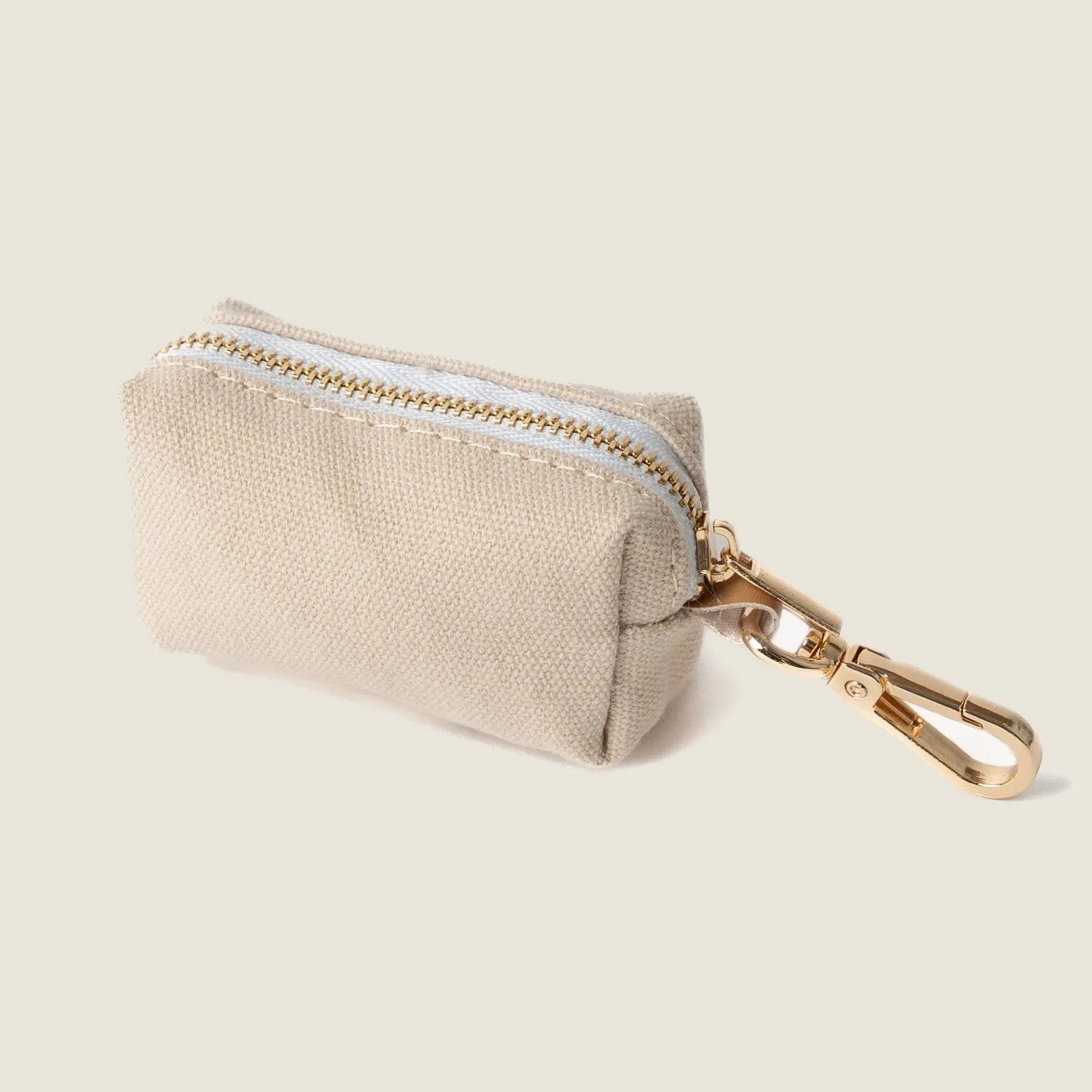 Tan poop bag holder by FURLOU with a gold clip, featuring a compact design and zipper closure. Perfect for dog walking.
