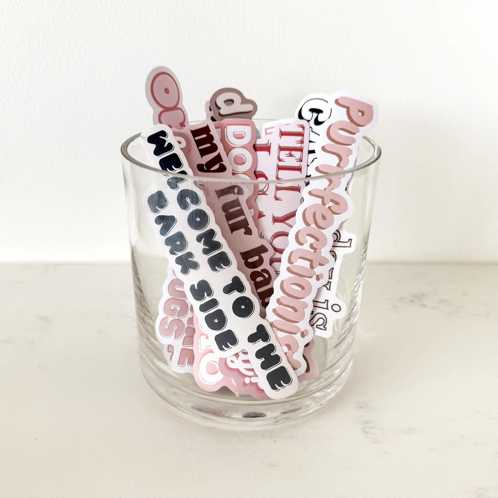 Colorful dog-themed stickers in a glass cup, featuring playful phrases like "Tell Your Dog I Said Hi" and "Bark Side."