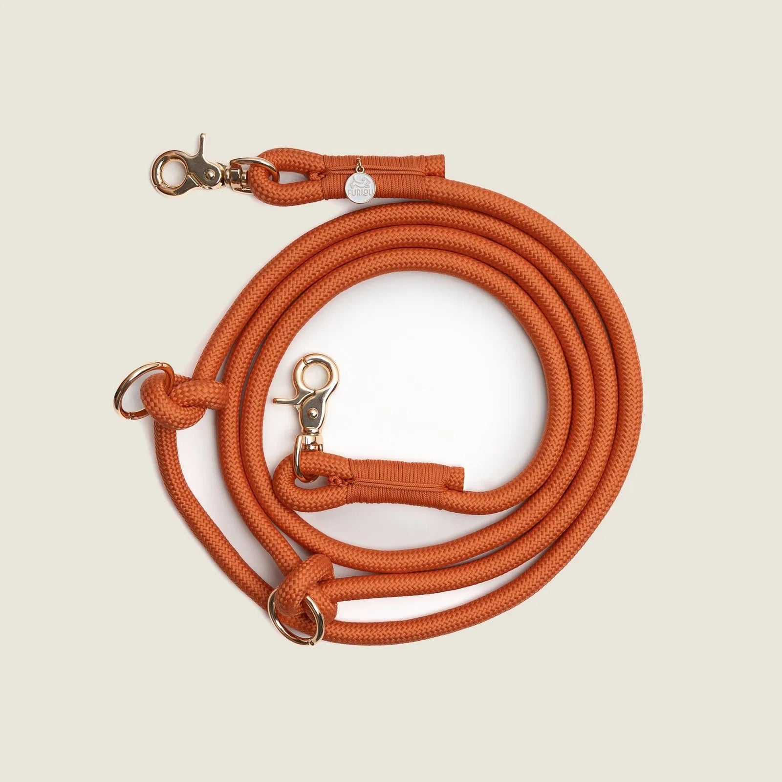 Terracotta hands-free braided leash with gold hardware, coiled neatly against a light background.