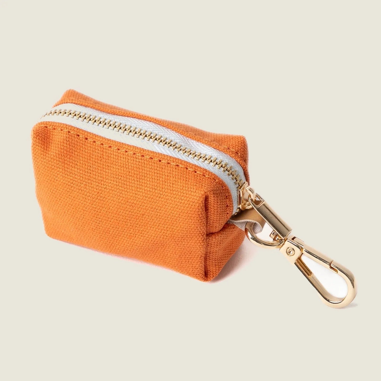 Stylish terracotta poop bag holder by FURLOU with gold clip and zipper, designed to hold essentials during walks.