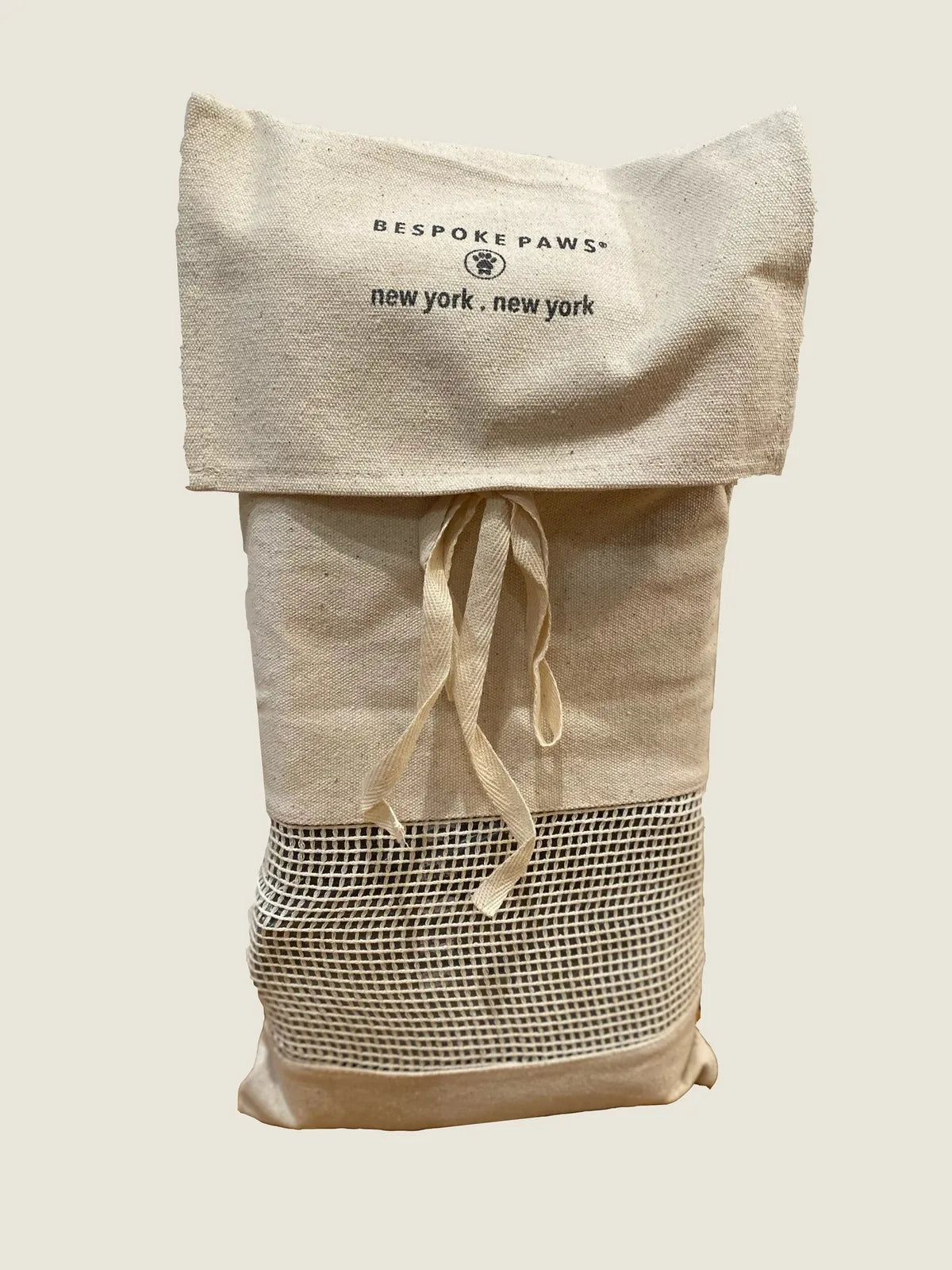 Natural beige pet carrier with mesh bottom, featuring BESPOKE PAWS logo, adjustable drawstring closure, and stylish design.