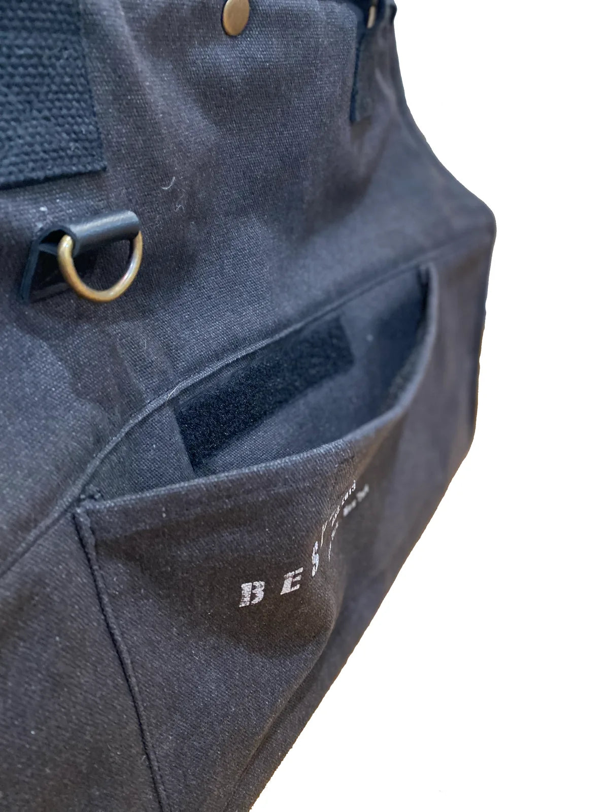 Black recycled cotton canvas pet carrier with a front pocket and gold hardware detail, designed for stylish travel.