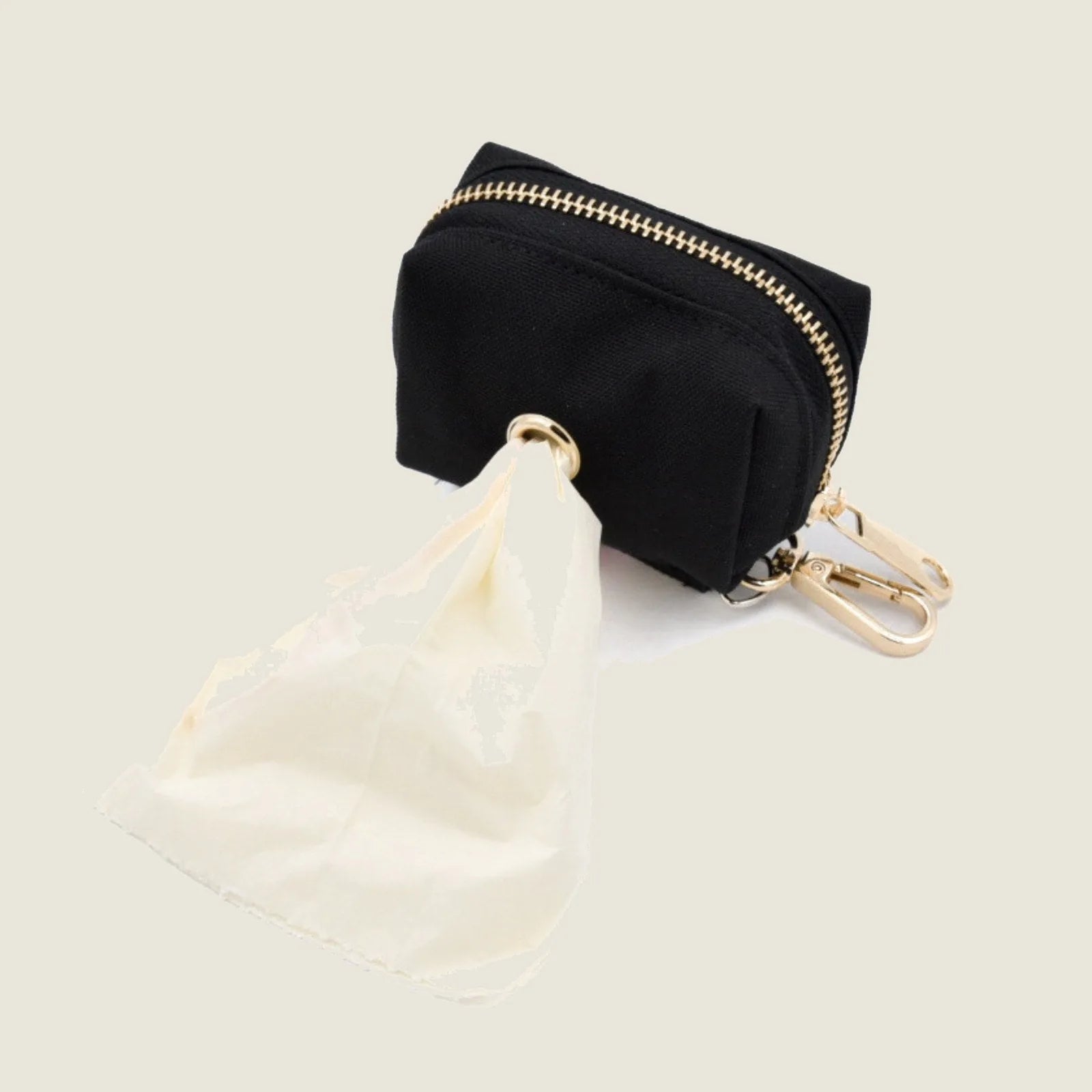 Black poo pouch with gold zipper, featuring a white bag partially pulled out, attached with a gold clasp.