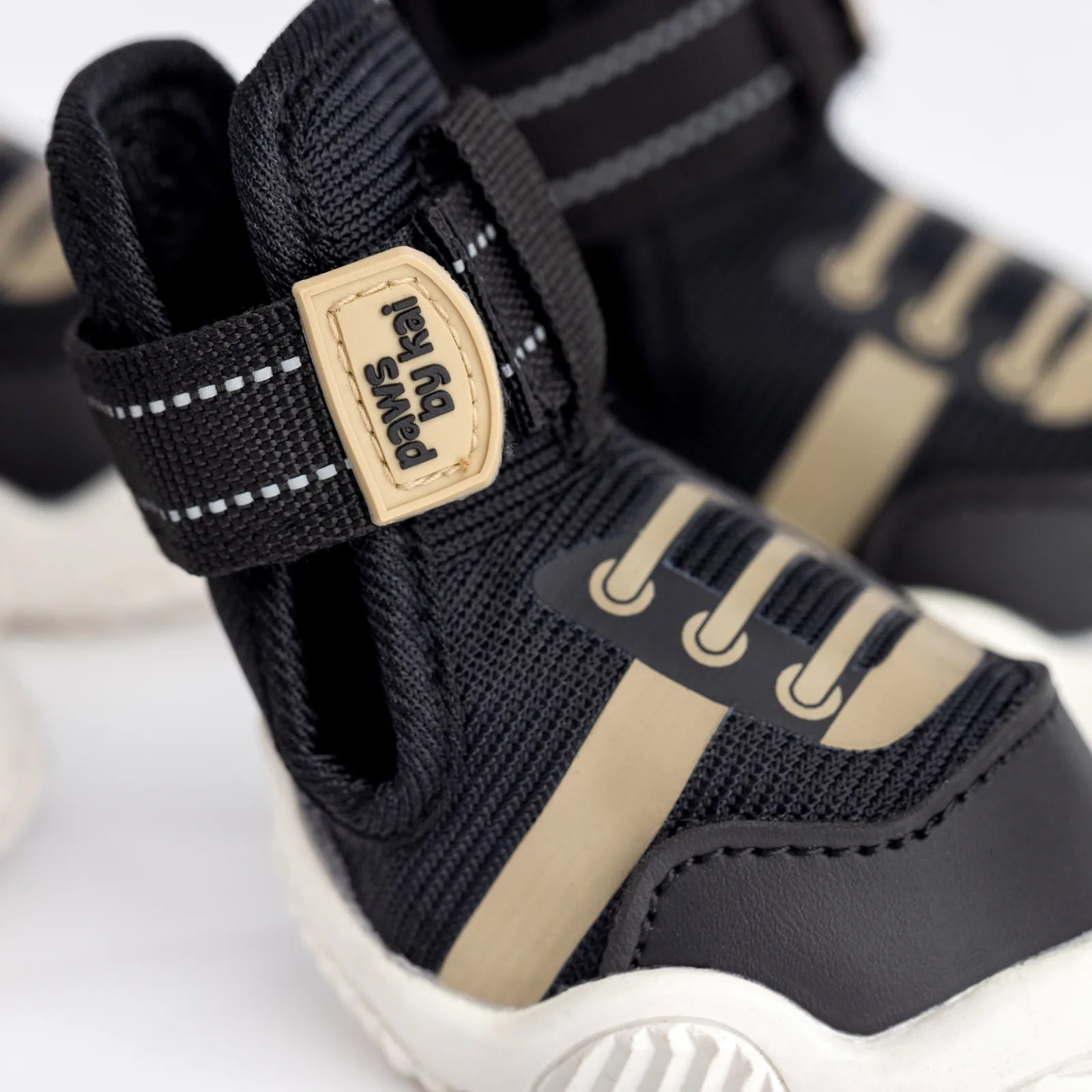 Adjustable black dog sneakers with a sleek design, featuring a beige stripe and logo by Paws By Kai.