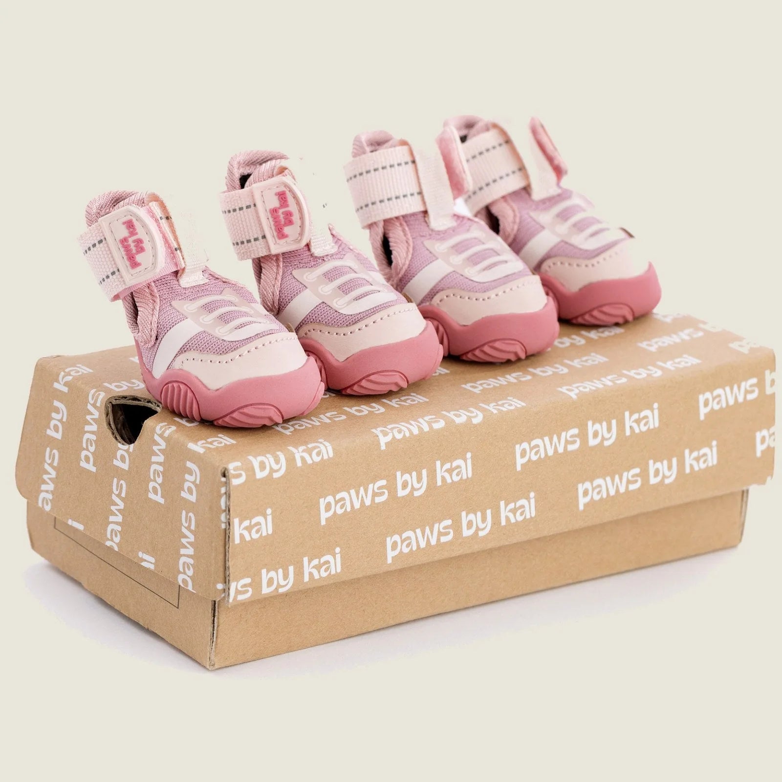 Pink dog sneakers with adjustable straps resting on a branded box, featuring a sporty design suitable for outdoor use.