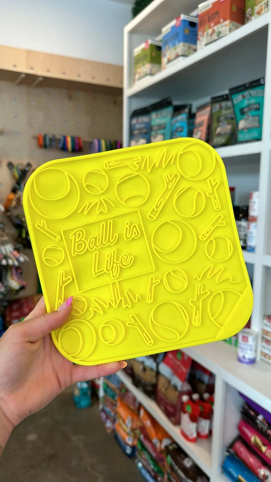 Bright yellow silicone lick mat featuring playful ball and stick designs, ideal for dog feeding and enrichment.