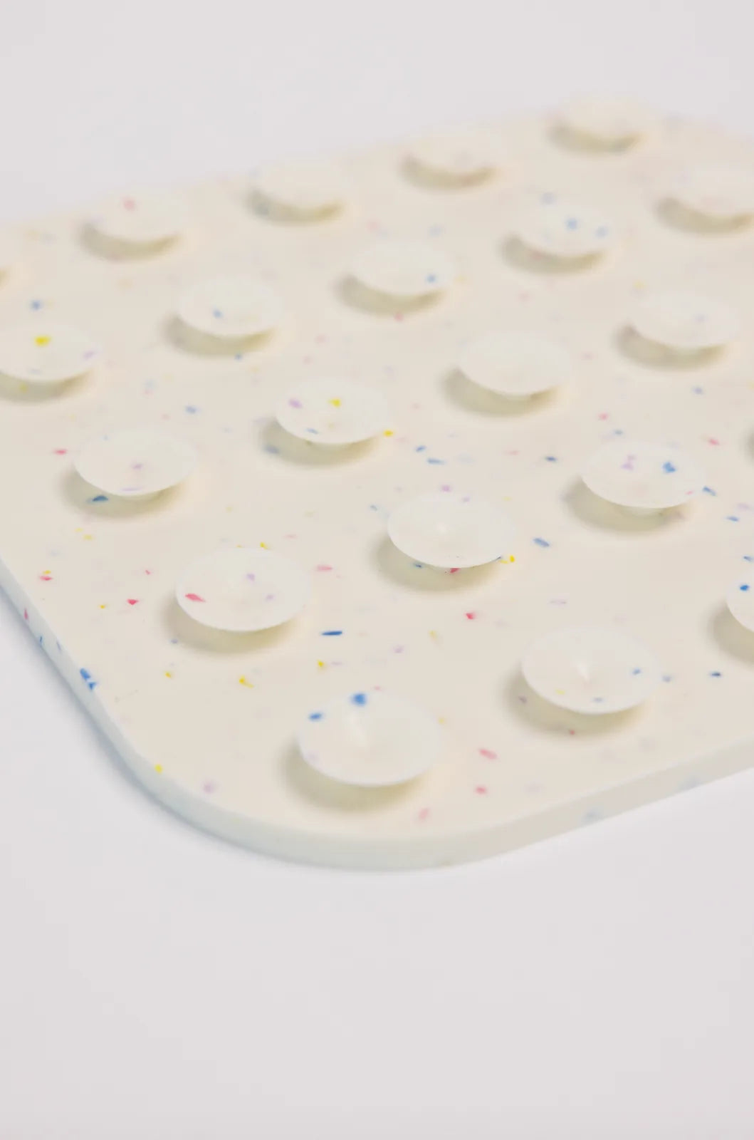 Lick mat in off-white silicone with colorful speckles, featuring suction cups for stability during feeding.