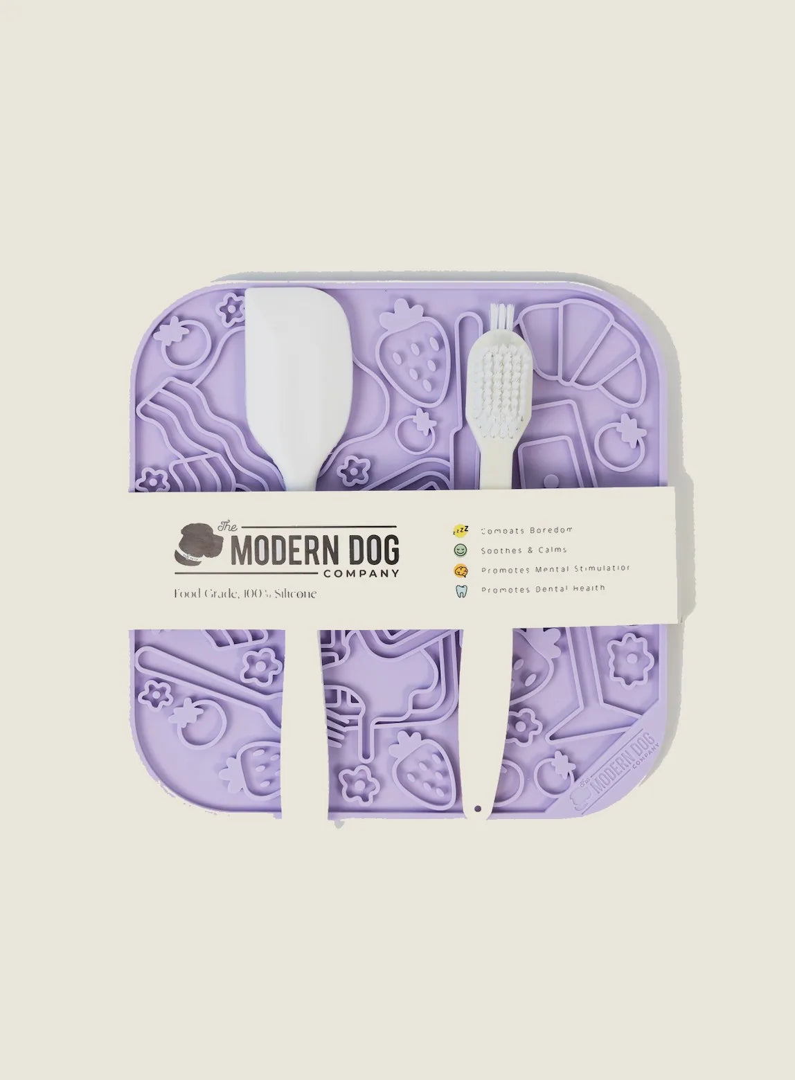 Lilac silicone lick mat with textured patterns, a spatula, and scrub brush for dog feeding and stimulation.