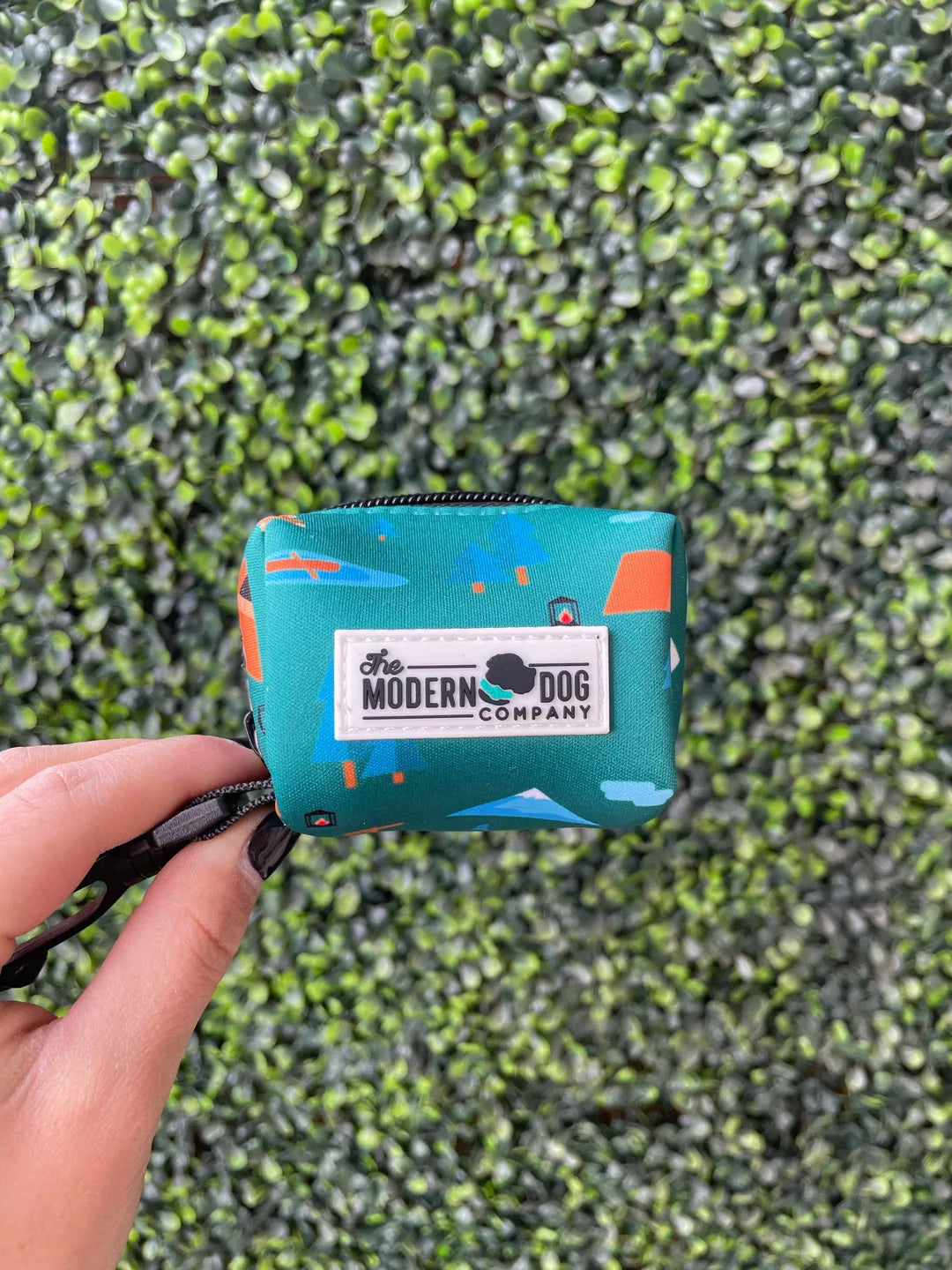 Camping print neoprene poop bag holder in teal, holding a roll of waste bags, with The Modern Dog Company logo.