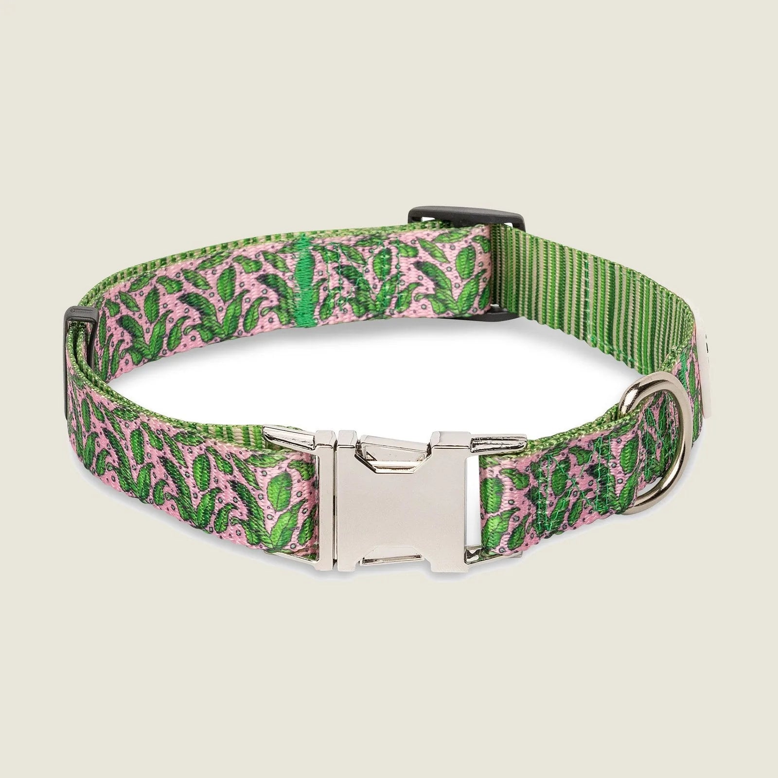 Adjustable dog collar in pink and green tropical pattern, featuring a durable metal buckle and D-ring for leash attachment.