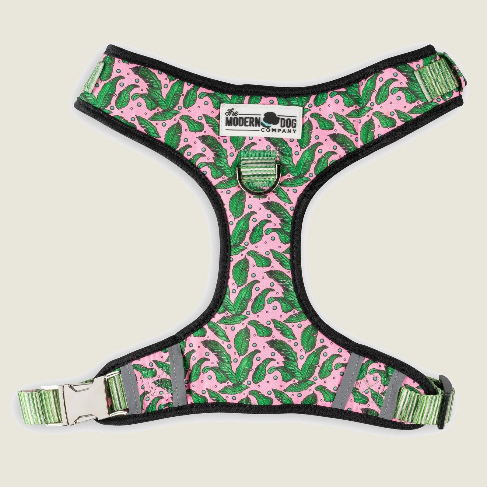 Adjustable pink dog harness with green leaf pattern and black trim, featuring two leash attachment options.