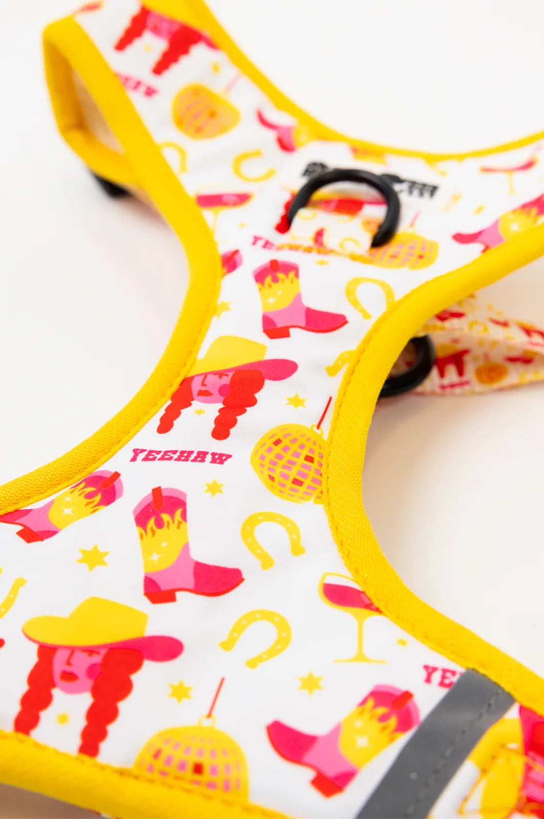 Colorful dog harness featuring a lively Yeehaw design with pink and yellow patterns, including boots and stars.