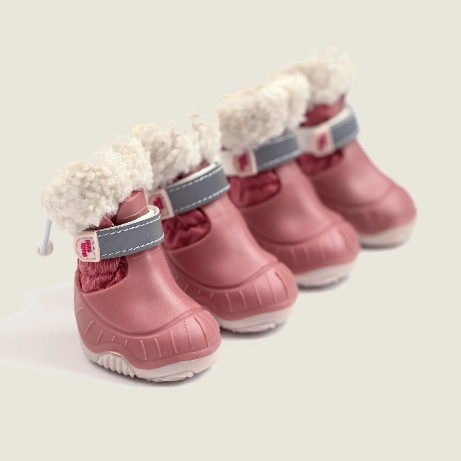 Pink waterproof dog snow boots with a plush sherpa lining and adjustable straps, lined up for winter adventures.