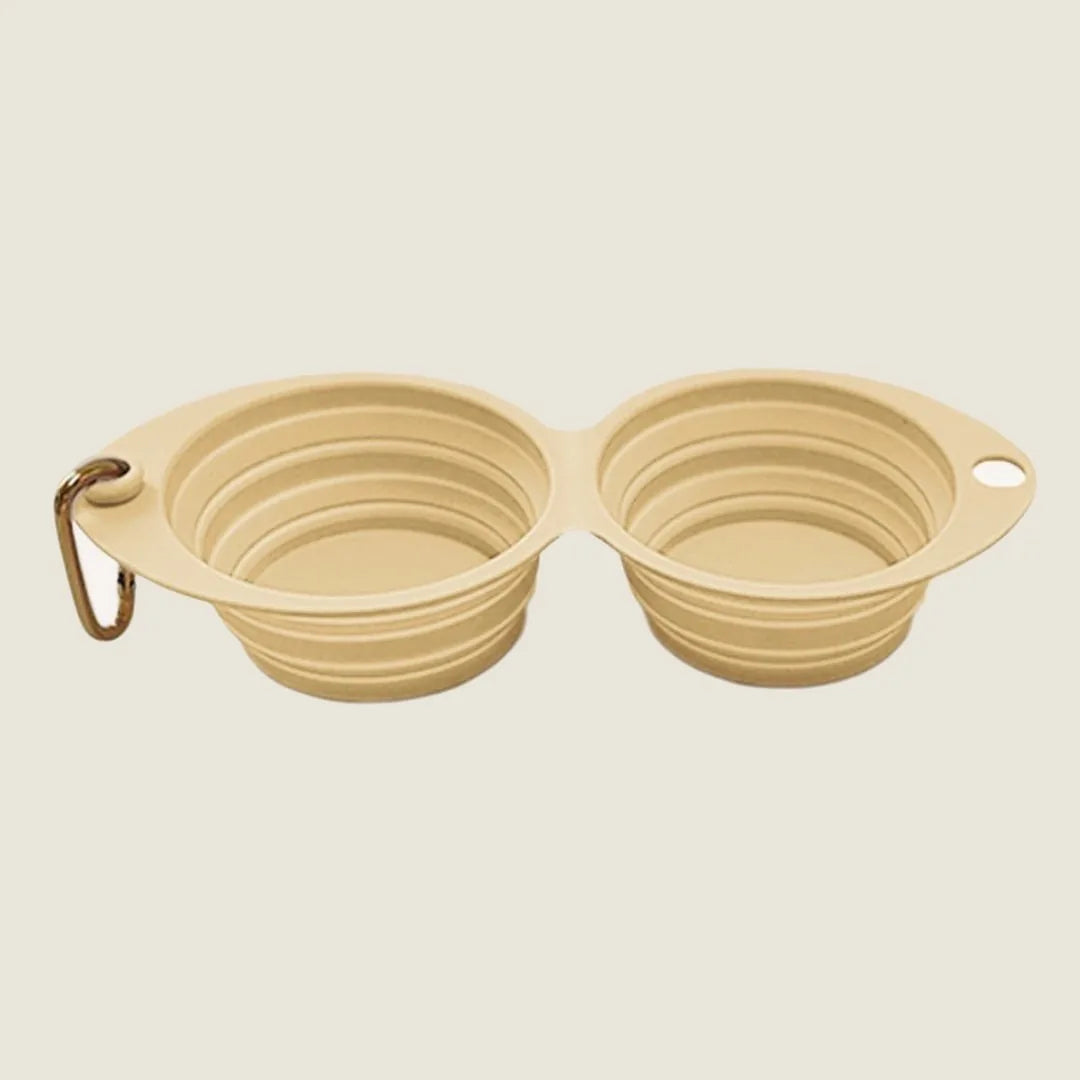 Collapsible double pet bowl in light banana color, featuring two compartments and a clip for easy portability.