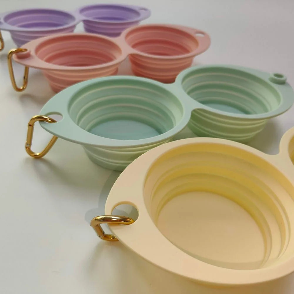 Collapsible double pet bowls in Banana, Lilac, Pink, and Mint Green, featuring gold clips for easy travel.