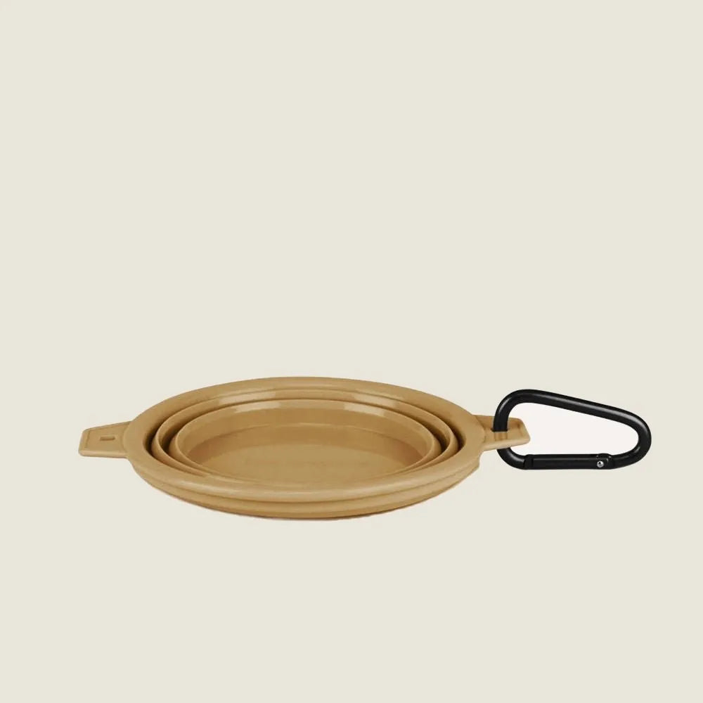 Collapsible beige travel pet bowl with a black clip, designed for easy attachment and portability.