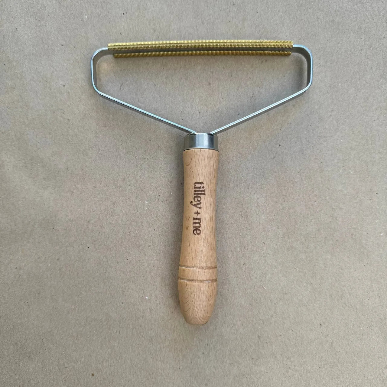 Eco-friendly beech wood lint remover with a metal handle, designed to effectively remove pet hair from fabrics.