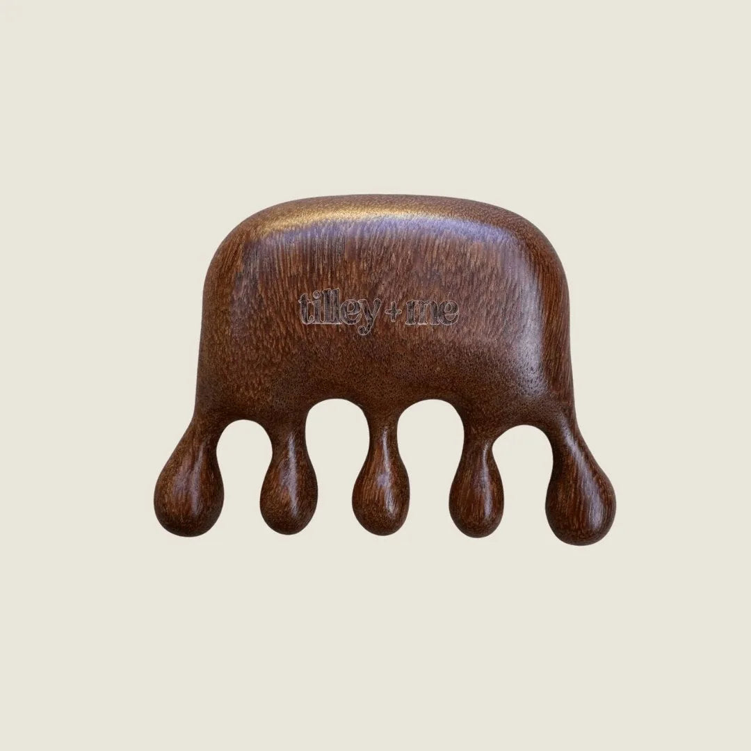 Sandalwood pet massage tool with five rounded prongs, featuring the engraved text "tilley + me." Ideal for grooming.