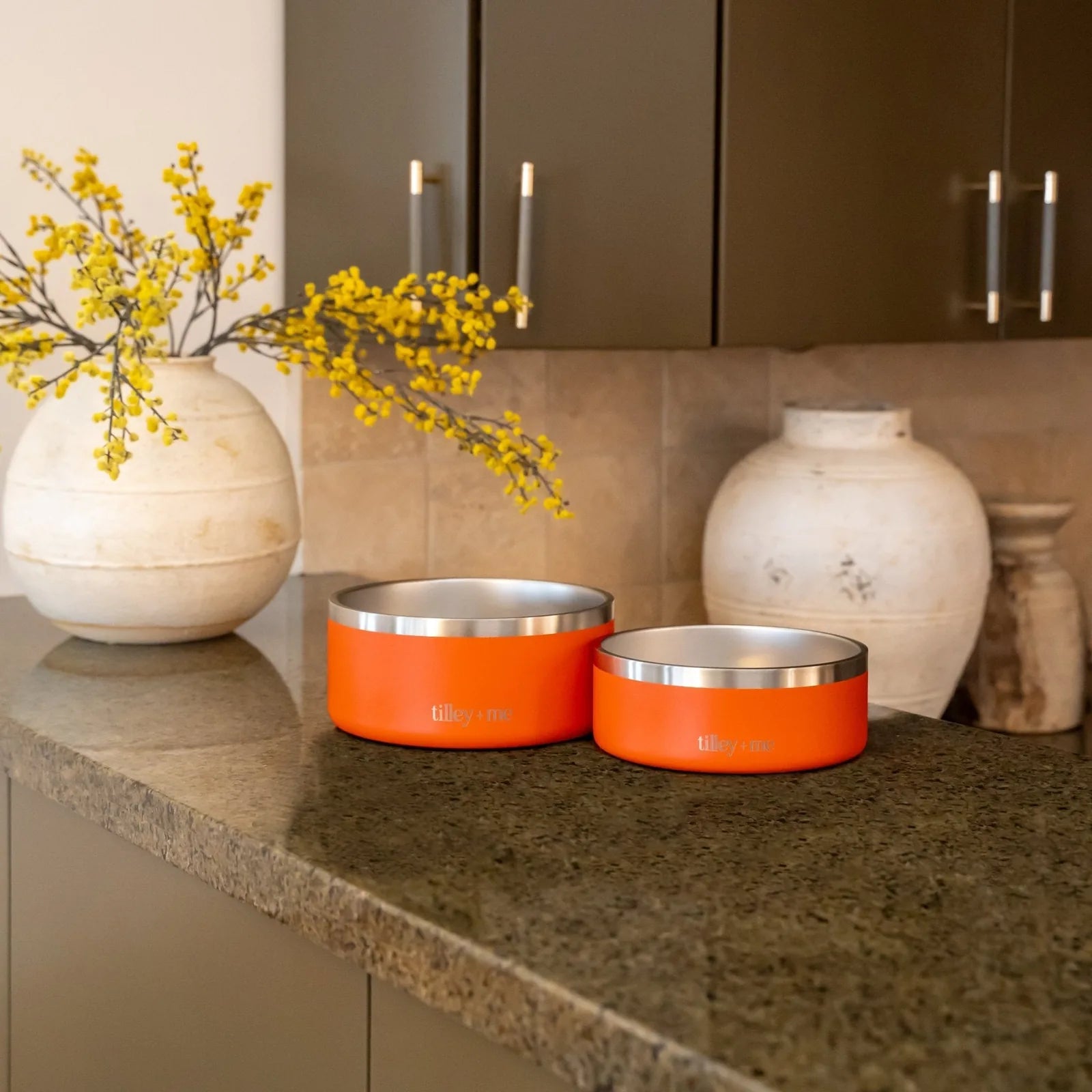 Terracotta Rose stainless steel pet bowls by Tilley + Me on a granite countertop, featuring a non-slip base.