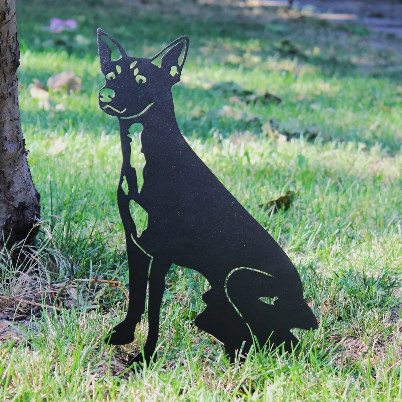 Black metal silhouette of a Toy Fox Terrier sitting in grass, designed for outdoor decor by My Metal Rescue.