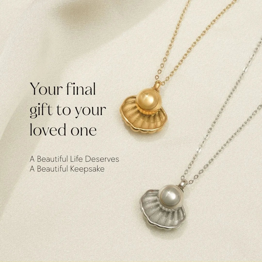 Silver and gold cremation necklaces with shell and pearl motifs on a soft fabric background.