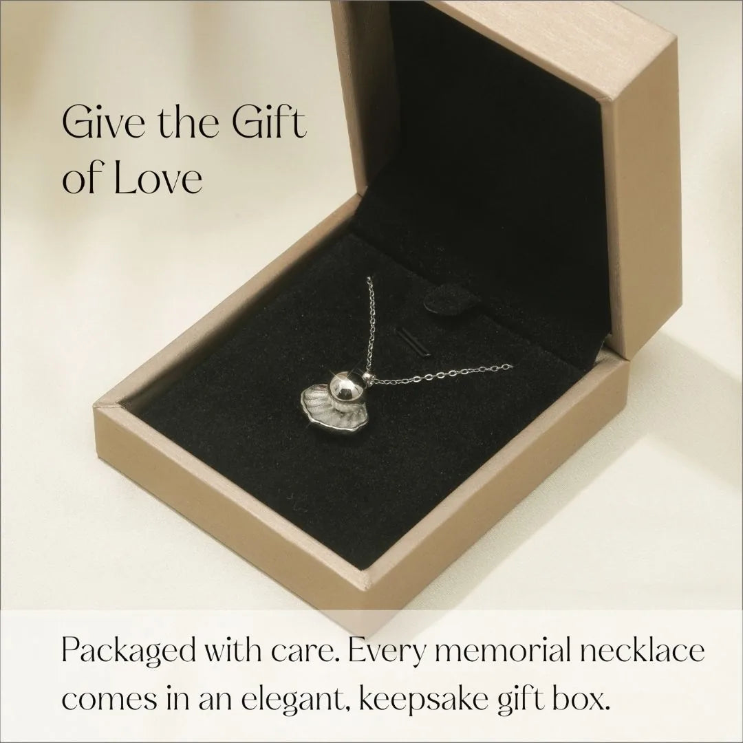 Silver cremation necklace with a shell and pearl design in an elegant keepsake gift box, ready for memorial use.