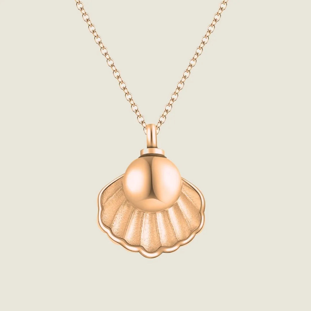 Rose gold memorial necklace shaped like a shell, designed to hold ashes, on a delicate chain.