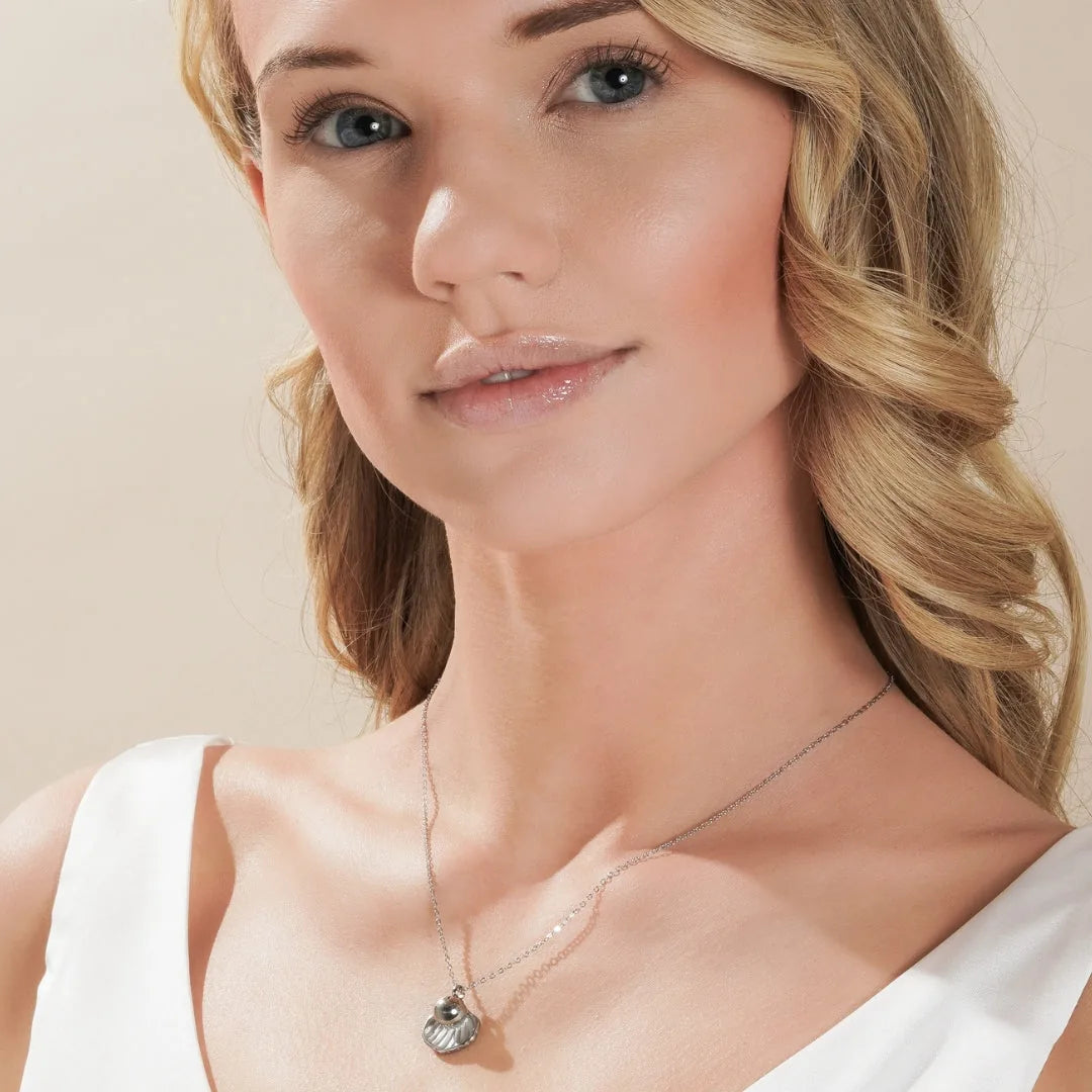 Silver treasure memorial necklace featuring a shell design, delicately worn, symbolizing love and remembrance.
