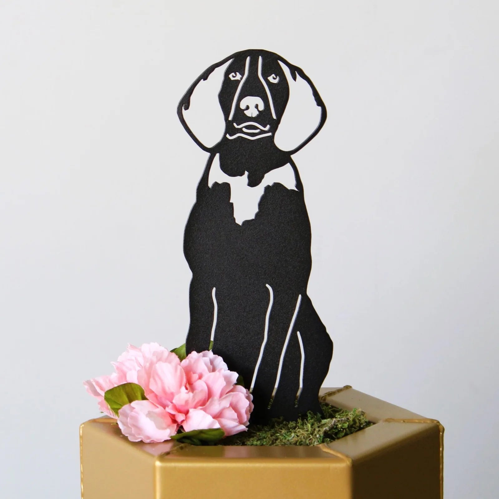 Black metal silhouette of a Treeing Walker Coonhound sitting among pink artificial flowers in a decorative planter.
