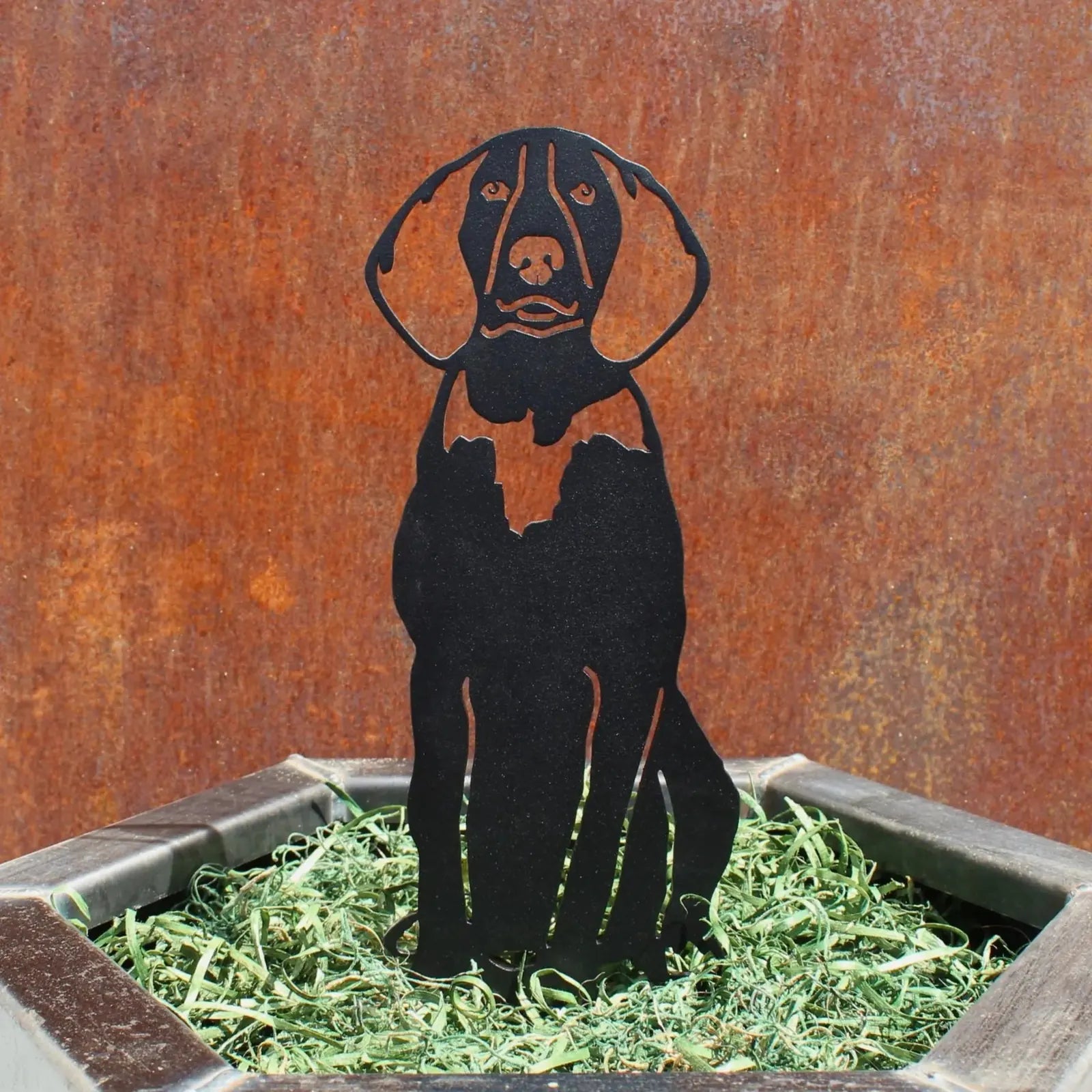 Black metal silhouette of a Treeing Walker Coonhound displayed in green grass, set against a rusty background.