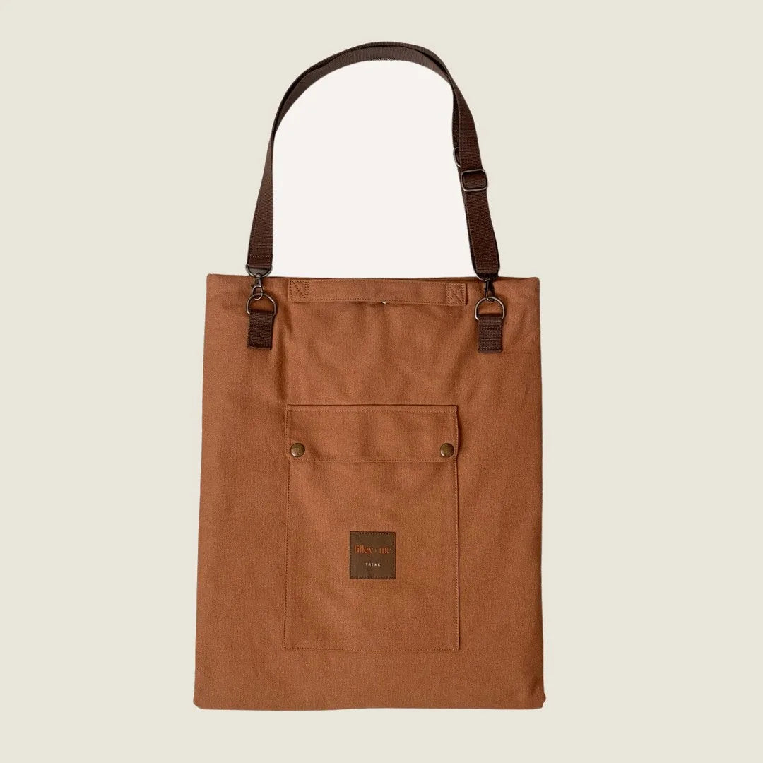 Brown canvas mat with adjustable straps and a front pocket, designed for travel, camping, and picnics.