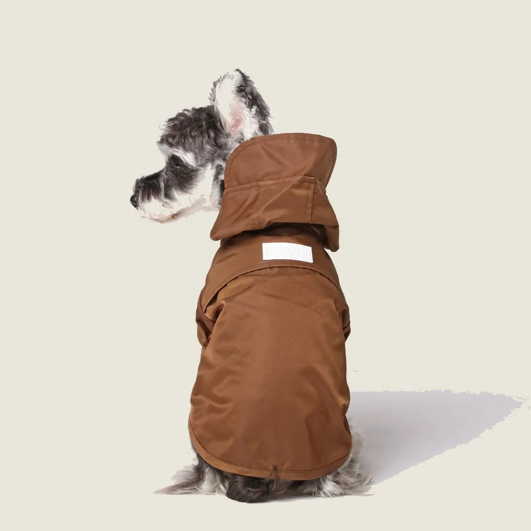 Brown adjustable raincoat for dogs, featuring a hood and Velcro closures, showcased on a dog in profile.