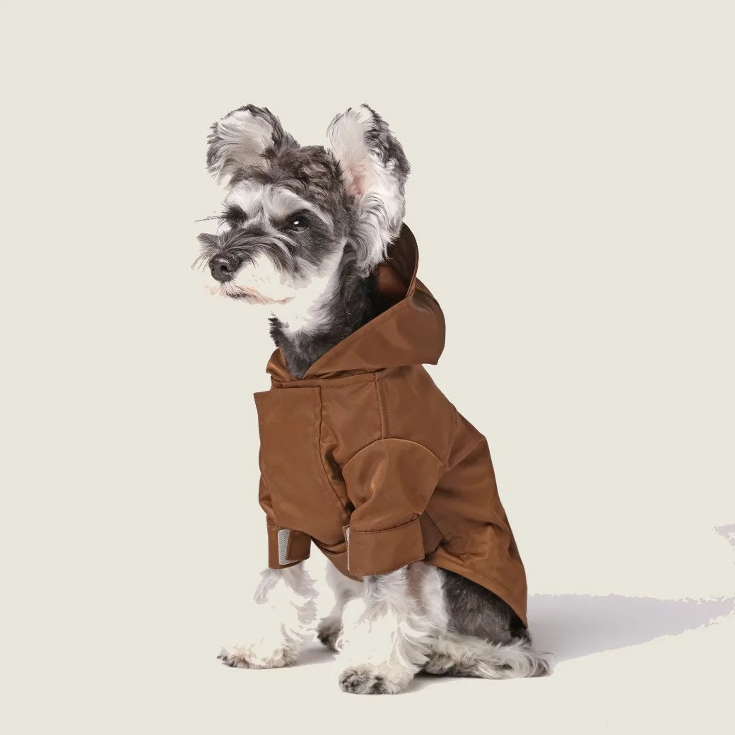 Brown adjustable Velcro raincoat on a small dog, featuring a hood and cuffs for a snug fit.