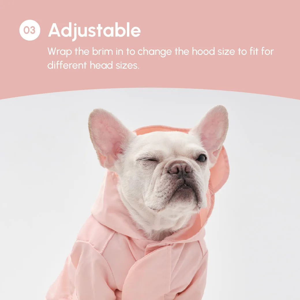 Light pink adjustable raincoat with a hood on a dog, showcasing a relaxed fit and a stylish design.