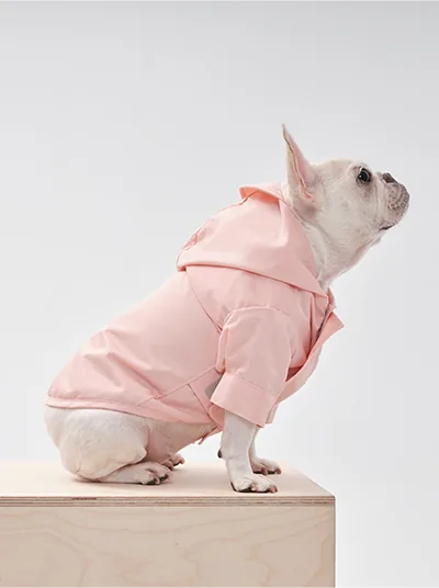 Light pink adjustable raincoat with a hood, designed for dogs, featuring velcro closures and stylish cuffed sleeves.