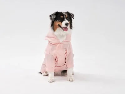 Light pink adjustable raincoat on a dog, featuring a hood, velcro closures, and a snug fit design for comfort.
