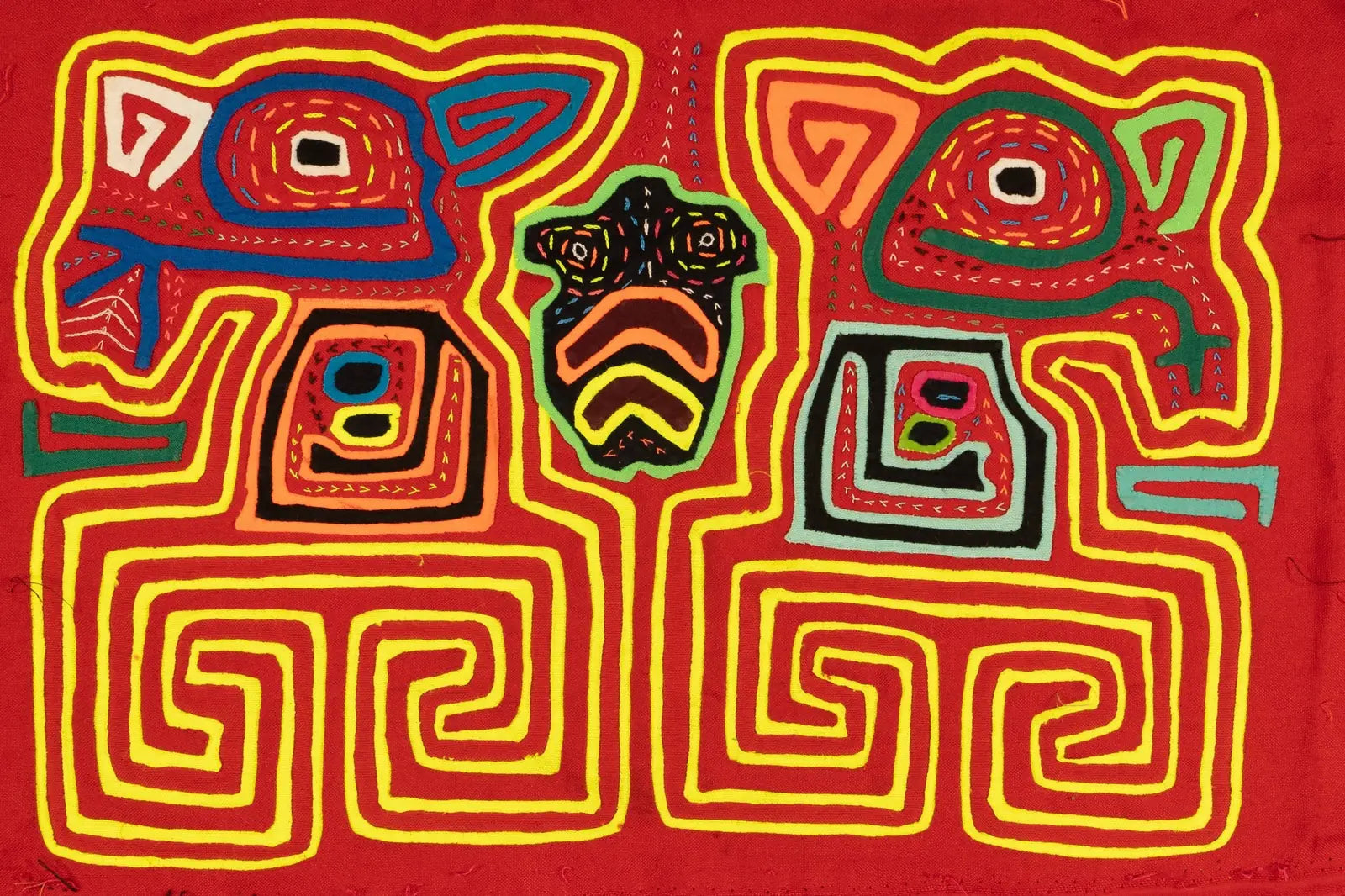 Hand-stitched red tapestry featuring vibrant geometric patterns and animal motifs in layered fabrics.