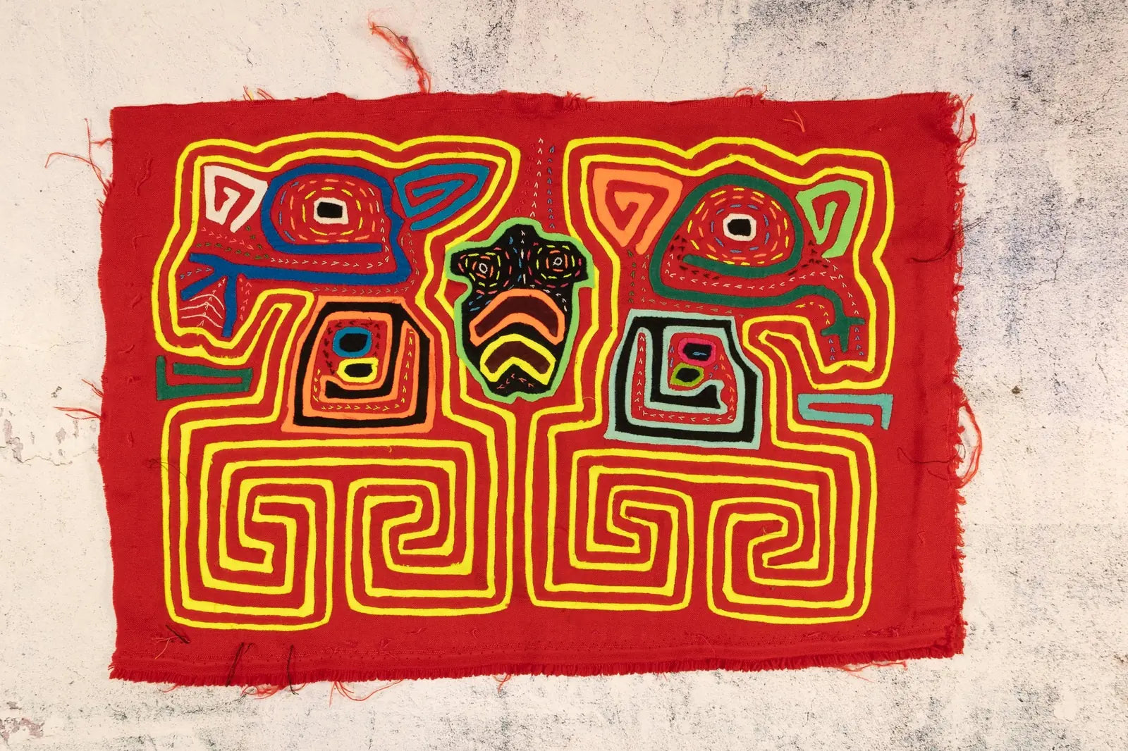 Hand-stitched red Mola tapestry featuring vibrant geometric patterns and indigenous designs by Guna artisans from Panama.