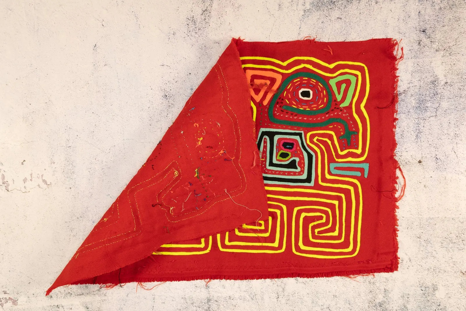 Hand-stitched true red Mola tapestry featuring colorful geometric patterns and designs by indigenous Guna artisans.