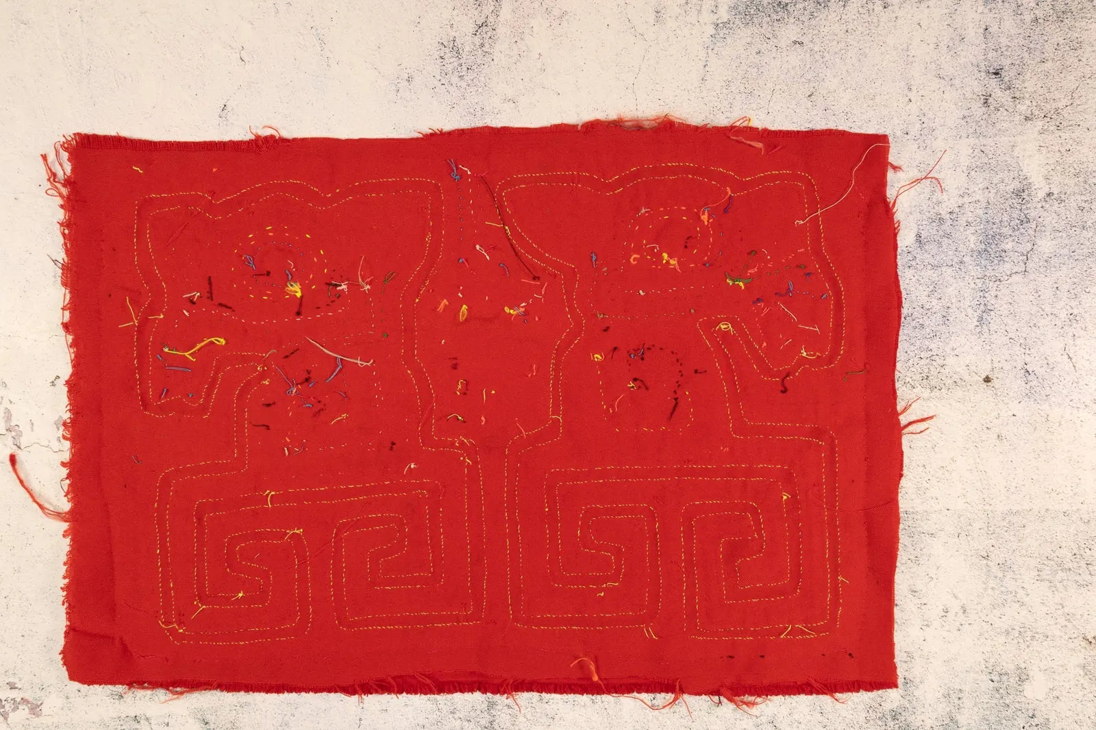 Bright red tapestry featuring hand-stitched puppy design with colorful thread accents, showcasing traditional Mola craftsm...